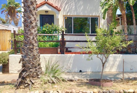 Charming Spanish-style bungalow at 3714 Dwight Street in Cherokee Point with a white stucco exterior, dark wood fencing, and tropical landscaping.
