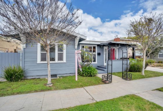 Charming residence at 3012 Dwight Street showcasing classic Craftsman bungalow architecture with blue horizontal siding and crisp white trim. The front exterior features a vibrant red door that provides a bold pop of color and a welcoming entrance.