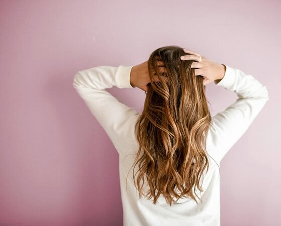 pexels-photo-973401-973401 Back view of a woman with elegant long brown hair against a pink wall, showcasing stylish hair design.