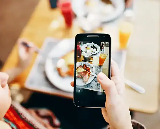 Frühstücksfoto mit Smartphone aufgenommen Person fotografiert Frühstück mit Smartphone, Essen auf dem Tisch.