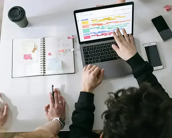 Effektive Content-Planung für digitales Marketing Person arbeitet an digitalem Content-Plan auf Laptop mit Kalender und Smartphone.