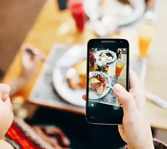 Frühstücksfoto mit Smartphone aufgenommen Person fotografiert Frühstück mit Smartphone, Essen auf dem Tisch.