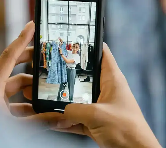 Modenschau im Modegeschäft Person filmt Modepräsentation im Geschäft mit Smartphone.