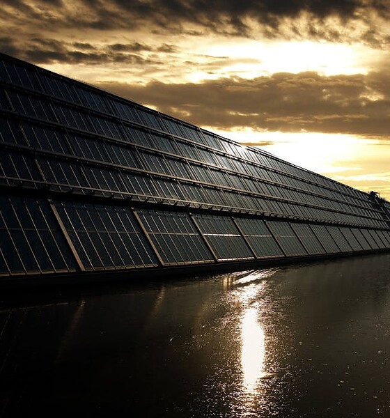 Silhouetted solar panels reflect sunset in tranquil waters, showcasing renewable energy.