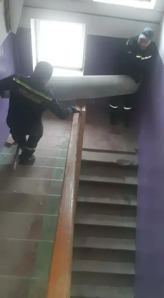 Рятувальники переносять уламок ракети у під’їзді
