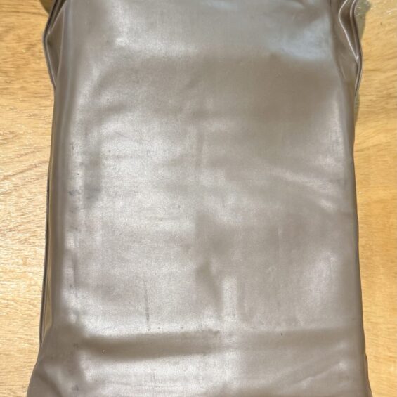 Dark gray vinyl tote bag with two rectangular handle openings at the top on a wooden table.