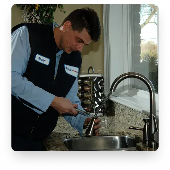 A plumber from Drain Rescue fixing a kitchen faucet using a wrench at a residence in Etobicoke