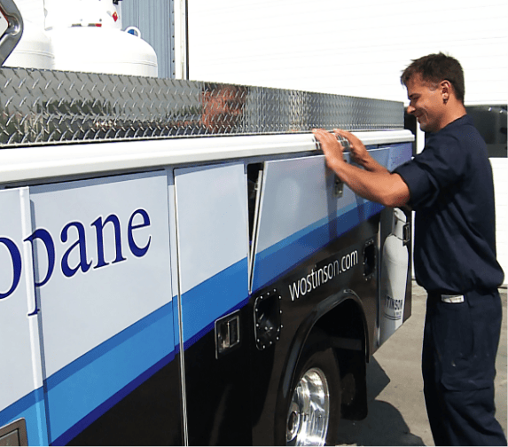 An image portrays a young man on a service call as he opens the side panel on a truck to access equipment