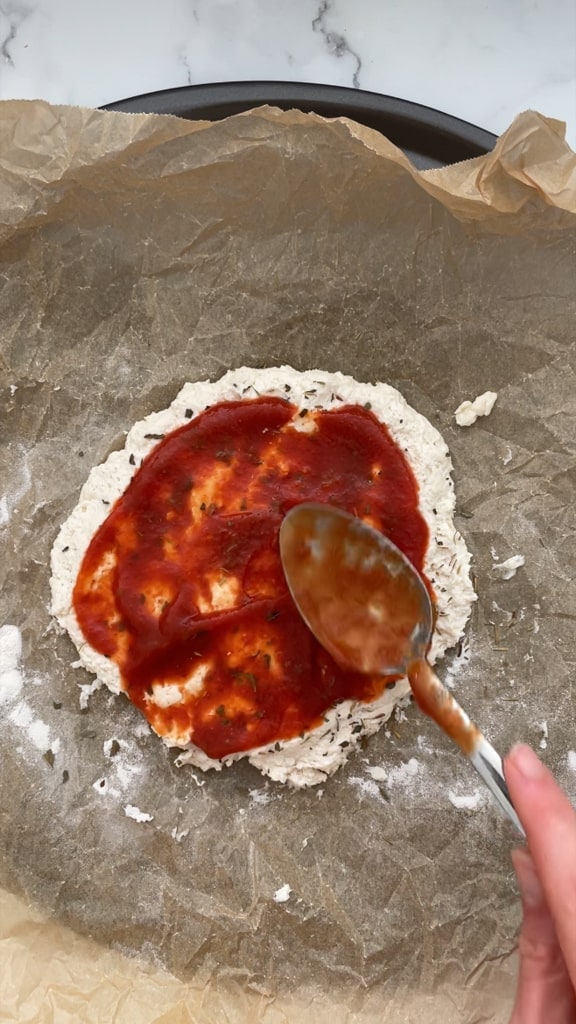 Spooning the sauce on top of the dough.