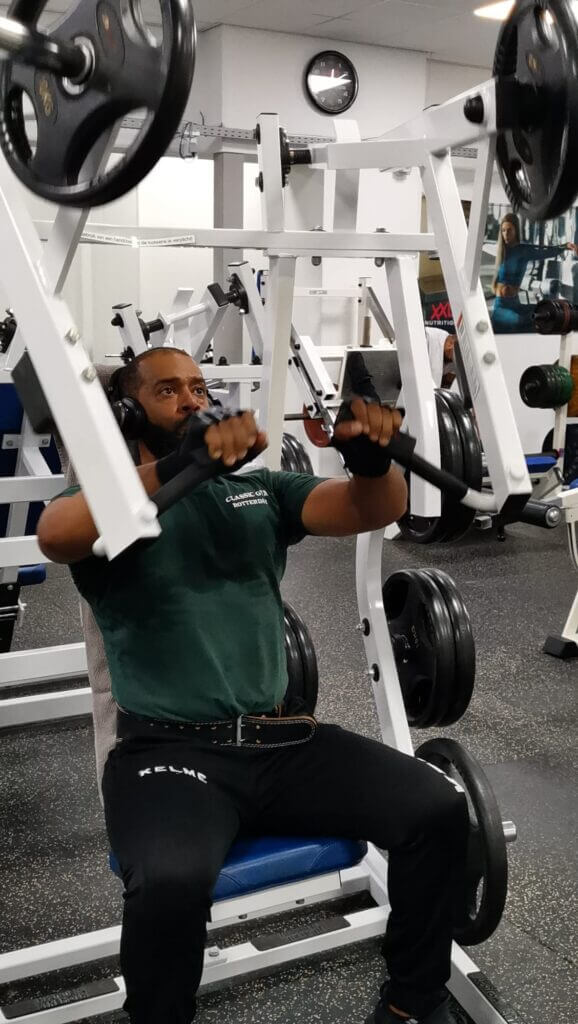 Man voert een incline chest press uit op een Hammer Strength free-loaded machine, gefocust op kracht en stabiliteit.
