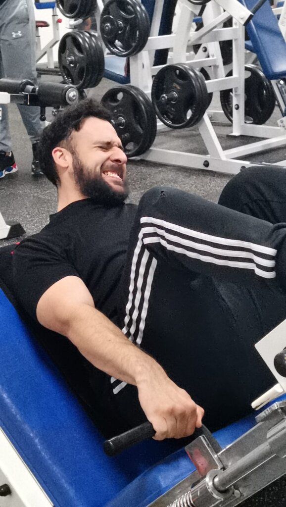 Een man voert een leg press uit op een fitnessapparaat, gefocust op kracht en gemotiveerd om zijn grens te verleggen.