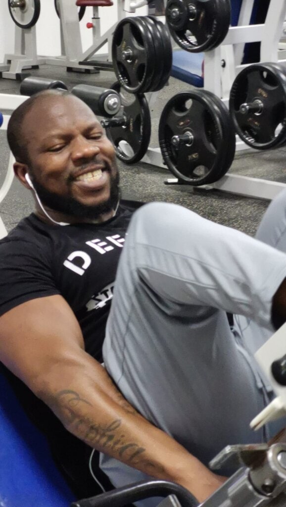 laat je motiveren en kom grenzen verleggen. Een man voert een leg press uit op een fitnessapparaat, gefocust op kracht en controle tijdens zijn training.