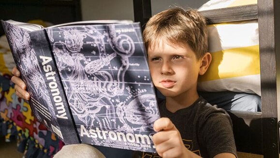 child reading a book about astronomy