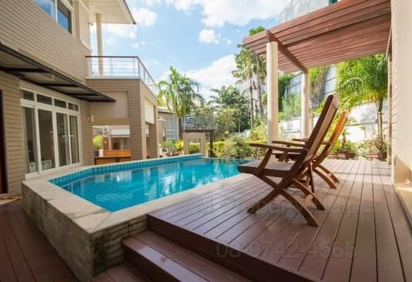 Modern backyard with rectangular pool, wooden deck, lounge chairs, and pergola