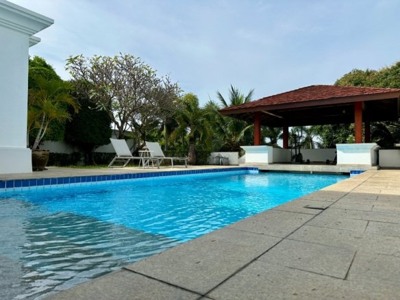 Luxury resort swimming pool with lounge chairs and tropical garden landscape