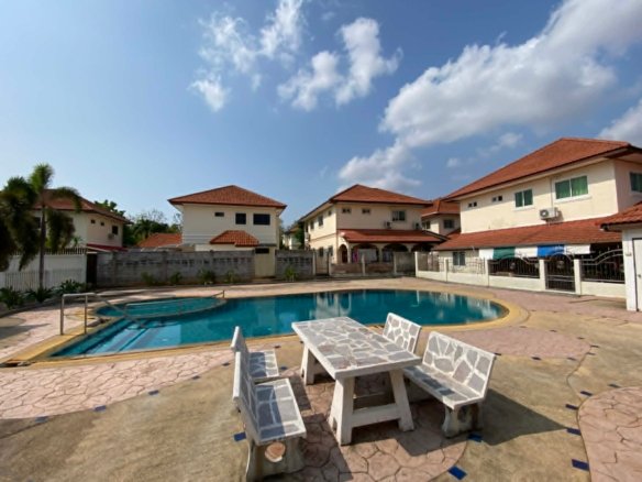 Residential community swimming pool with white furniture and two-story homes