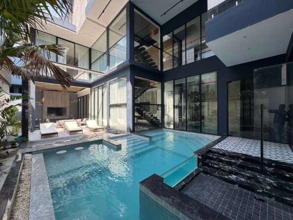 Modern luxury home with turquoise swimming pool and dark architectural design