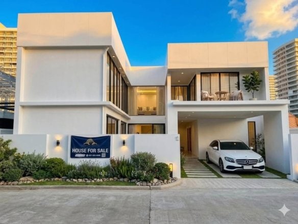 Modern white house with geometric design, carport, and for sale sign