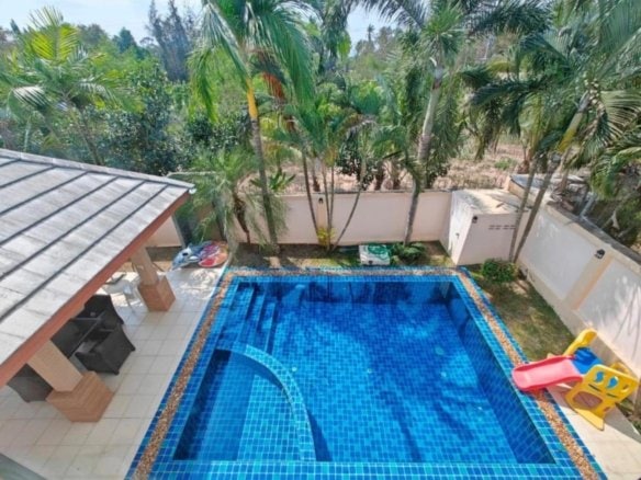 Aerial view residential swimming pool surrounded by palm trees and patio area
