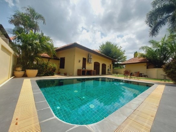 Luxury villa with swimming pool, yellow walls, and tropical gardens