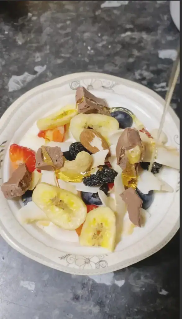 Honey is being drizzled over yogurt fruit parfait.