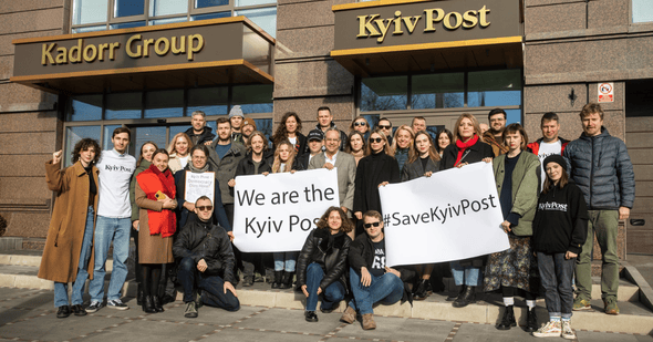 The Kyiv Post's former editorial team posing with posters to save the newspaper.