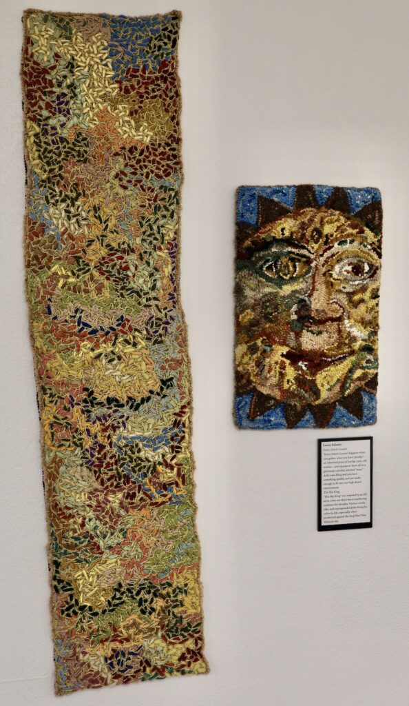 Two wall hangings, one abstract with stitches and one with a sun with a face