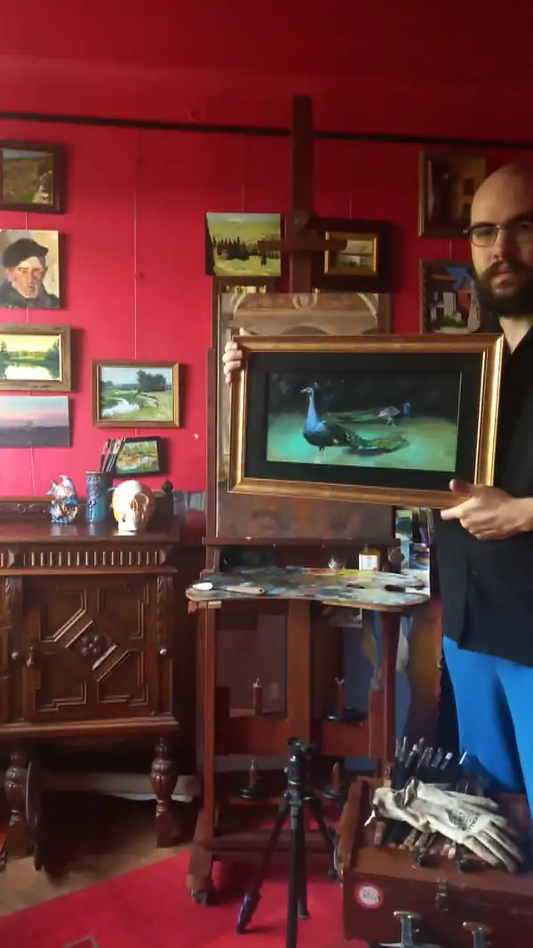 Artist holding framed Pavoni peacocks oil painting in the studio