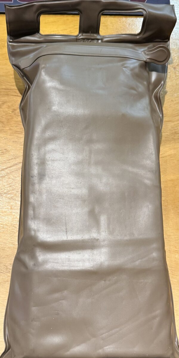 Dark gray vinyl tote bag with two rectangular handle openings at the top on a wooden table.