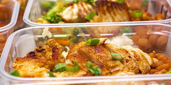 Colorful meal prep containers with grilled chicken, rice, and vegetables neatly packed.