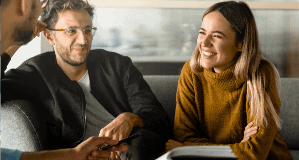 Coworkers sitting on a sofa. They are smiling.