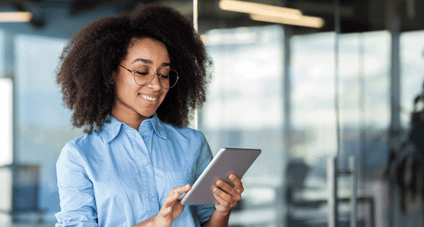 A woman looking at a tablet. She is smiling.