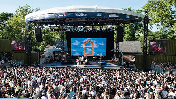 Outdoor music festival stage with rental LED display and large audience in an open event area