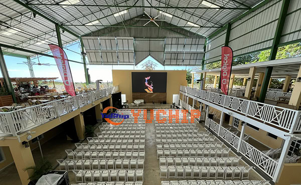 Long-shot view of the installed outdoor LED display during an event at a hotel venue in Barbados, with audience seating arranged in front of the screen