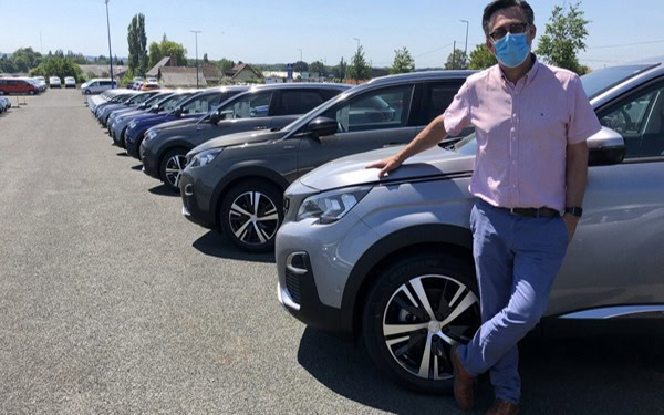 Christophe Glinche adossé à un véhicule dans le parc automobile