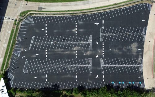 Aerial view of a new parking lot layout with fresh white stalls and crosshatch islands in Houston, TX