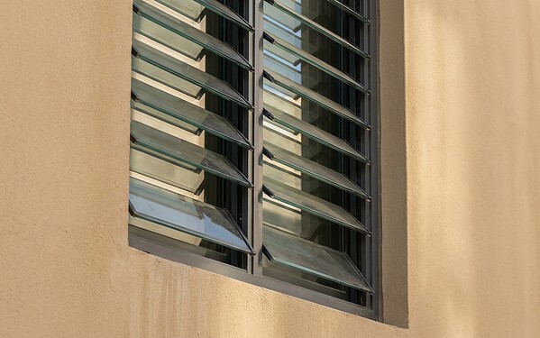 Aluminium ventilation louvre window with angled glass blades on a Dubai building wall