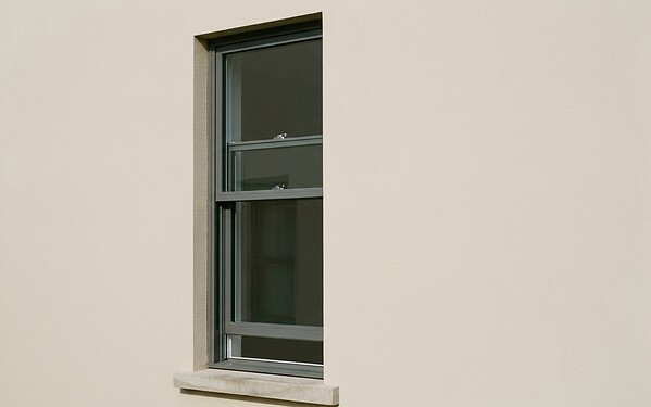 Double-hung aluminium sash window with two vertically sliding panes on a villa wall