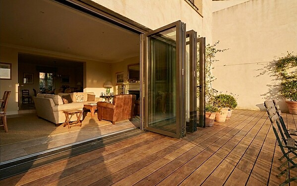 Sliding-folding hybrid aluminium glass doors open onto a villa terrace