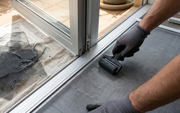 Technician re-meshing a torn mosquito screen with a spline roller tool