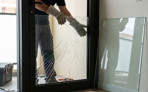 Technician replacing a cracked glass pane in an aluminium door frame