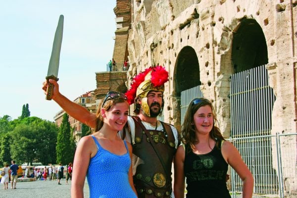 students standing with a gladiator in front of the coliseum in Rome