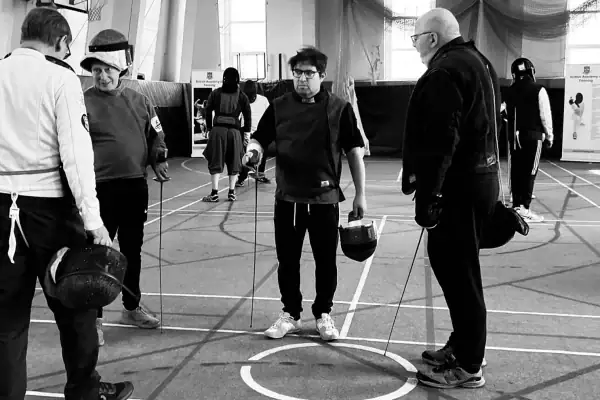 A group of trainee coaches receiving fencing instruction
