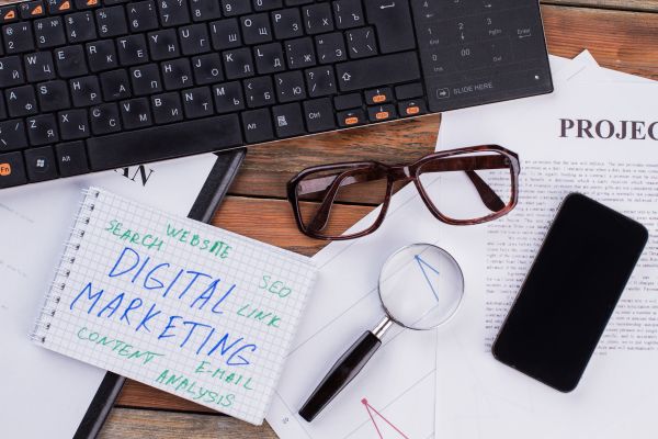 Digital Marketing On Notepad And Various Business Papers On Brown Background. - Auster Inteligência Contábil