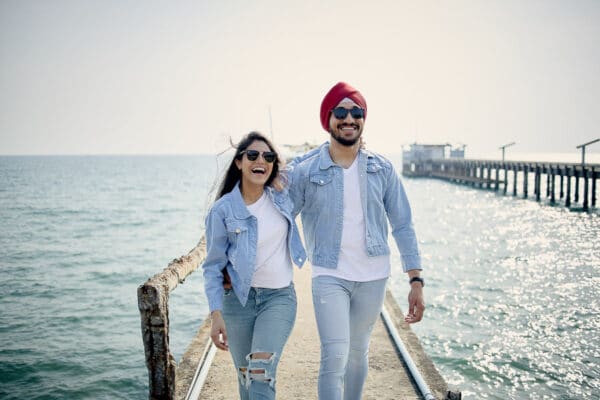 Sikh couple walking on a wooden sea pier during a pre-wedding photo shoot in Thailand