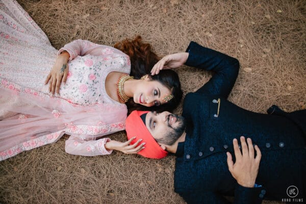 Sikh couple lying head to head on a rug in a playful pre-wedding portrait
