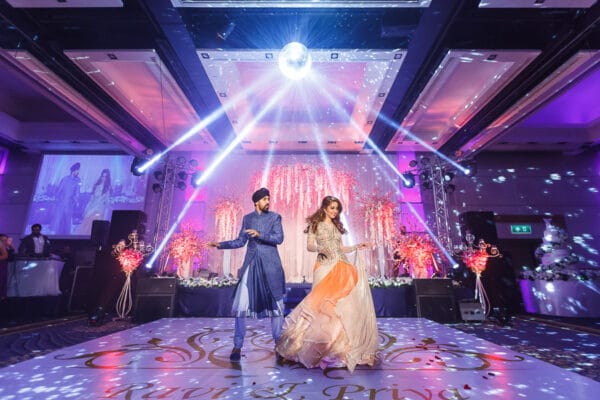 Bride and groom’s first dance on stage under purple lights at their Sangeet