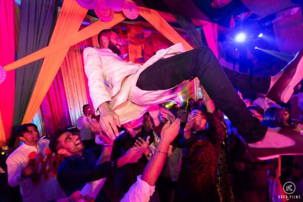 Guests lift the groom into the air on the dance floor at a Sangeet party