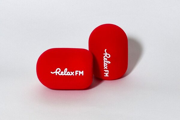 Relax FM branded studio microphone windshields with red cylindrical foam covers and white logo