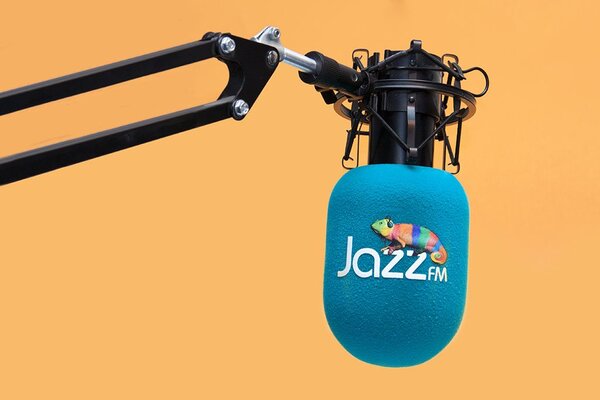 Jazz FM branded studio microphone windshield with blue cylindrical foam cover and colorful logo